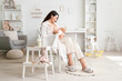 © Pixel-Shot - Young woman breastfeeding her little baby in armchair at home