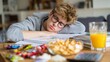 © Alena - Tired student sleeping on textbooks surrounded by snacks and juice at home desk. Student studying for SAT or ACT with prep books and practice tests, calculator and snacks on table