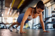 © Drazen - Female athlete doing push ups while exercising in gym.