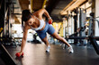 © Drazen - Athletic woman doing plank exercise with hand weights in gym.