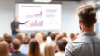 © Prapan - Business Presentation: A dynamic business presentation is underway, with an audience engrossed, as a presenter elucidates intricate data and insights on a large screen.