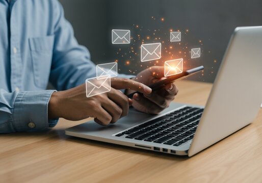 Glowing Email Icons Above Hands Using Laptop and Smartphone