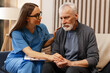 © Maria Vitkovska - Female doctor comforting sad senior man at home visit