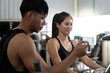 © Natee Meepian - Trainer assisting young woman during gym workout