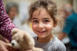 © Anastasiia Havelia - child receiving toy from volunteer in refugee shelter, genuine smile, soft lighting,