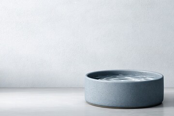 Poster - Minimalist grey bowl filled with water placed on a smooth surface in a serene indoor setting