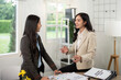 © Natee Meepian - Business Discussion. Two women engaging in a collaborative meeting in a stylish office.