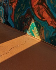Poster - Abstract Concrete Corner, A Warm Golden-Brown Surface Meets Vibrant Swirling Colors Under a Beam of Sunlight