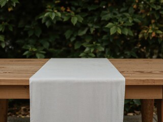 Poster - Elegant Creamy Table Runner on a Warmly Lit Natural Wood Table with a Lush Green Foliage Backdrop for a Serene and Inviting Setting