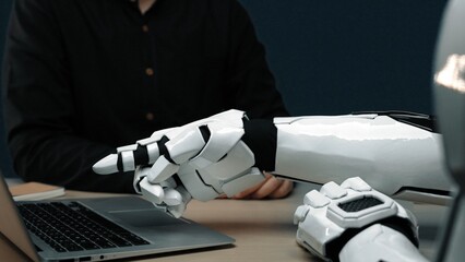 Poster - A futuristic robotic arm points towards a laptop, highlighting the blend of advanced technology and human-like interaction in a modern workspace setup.Noogenesis