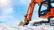 © photo for everything - Orange excavator on a snowy terrain against a blue sky. Tracks show it's working, suggesting construction or snow removal in cold conditions.