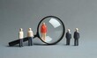 © Rezuan - The leader and his team stand near a magnifying glass on a gray background. Human resources, management. The concept of the search for people and workers. Search for vacancies and work.