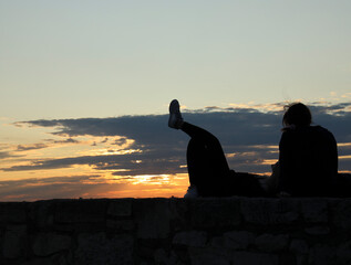 black silhouette of happy gay couple lying on sunset cloudy sky background lesbian women having a te
