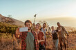 © Marko Geber - Diverse group of young people hiking and taking a moment to take a selfie with a smart phone overlooking a beautiful sunset and ocean