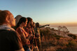 © Marko Geber - Diverse group of young people hiking and taking a moment to look at the beautiful sunset and ocean