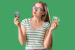 © Pixel-Shot - Young woman with credit card and cash on green background