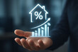 © techstudio - Business hand presenting real estate interest rate growth graph with percentage and house icon showing rising mortgage finance and investment trend in property market