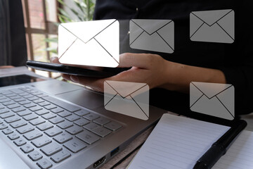Poster - Business person holding a cell phone while working on his computer and there are several email icons around