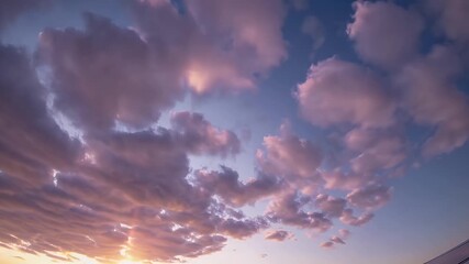 Wall Mural - Time lapse 4K footage captures cotton candy colored cumulus clouds transforming in a glowing sunrise sky offering a soft dreamy scene perfect for calming visuals and aerial perspectives