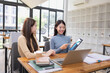 © SOMKID - Two Asian young businesswoman using laptop computer working in office,