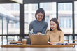 © SOMKID - Two Asian young businesswoman using laptop computer working in office,
