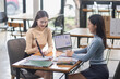 © SOMKID - Two asian Businesswoman using tablet and laptop reviewing digital financial graphs and reports working in office desk.