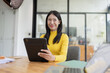 © SOMKID - Happy young Asian businesswoman using digital tablet sitting in office.