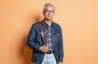 © Maryna - Mature Asian man with gray hair wears glasses, denim jacket over plaid shirt. Carries brown leather bag over shoulder, exuding casual yet smart style. Modern, confident, approachable demeanor,