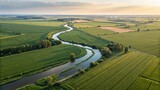 Aerial view of winding river through green fields at sunset, showcasing rural landscape