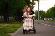 © twinstock11 - Mother and daughter face disability with joy and strength, daughter in wheelchair smiles during evening walk, disability shown through care, love, and everyday happiness.