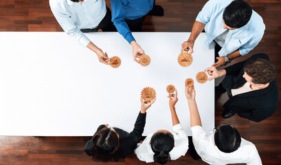 Poster - An overhead perspective of a diverse group of professionals engaging in a collaborative workshop session, using gears as a visual aid for problem solving and strategy development. Amity
