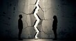 © soysuwan123 - Two silhouetted figures face each other, separated by a jagged crack in a concrete wall, symbolizing division or conflict.
