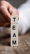 © Rucia - Wooden blocks spelling out the word team with a hand letters cooperation