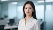 © Blithe - A woman in a white shirt stands confidently in an office environment.