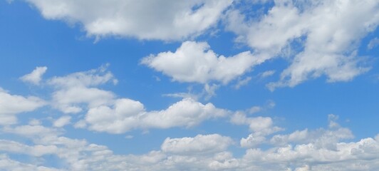 Wall Mural - Panoramic cloudscape in clear blue sky in summer. Nature sky background with fluffy clouds.