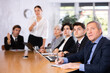 © JackF - Woman and man sitting at table beside her colleagues during meeting in conference room