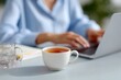 © Firadoaw - Professional woman working on a laptop at a tidy desk with a cup of tea and notebook
