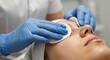 © Talha - Woman receiving facial treatment with cotton pads and blue gloves in a beauty salon setting