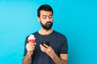 © luismolinero - Young man with a cornet ice cream over isolated blue background thinking and sending a message