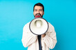 © luismolinero - Young handsome man with white corduroy jacket over isolated blue background shouting through a megaphone