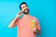 © luismolinero - Young man over holding a cocktail over isolated blue background thinking an idea