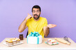 © luismolinero - Man in a table with a big cake making phone gesture and doubting