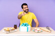© luismolinero - Man in a table with a big cake points finger at you with a confident expression