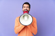 © luismolinero - Caucasian handsome man over isolated purple background shouting through a megaphone