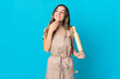 © luismolinero - Young Romanian woman holding a rolling pin isolated on blue background looking up while smiling