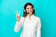 © luismolinero - Telemarketer Italian woman working with a headset isolated on blue background happy and counting three with fingers
