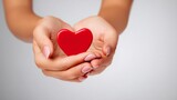 Dłonie trzymające czerwone serce na jasnym tle – symbol wsparcia, miłości i zaufania