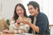 © surachetkhamsuk - Happy Asian family young couple in love hand holding model house and showing keys for saving money to buy real estate for new home