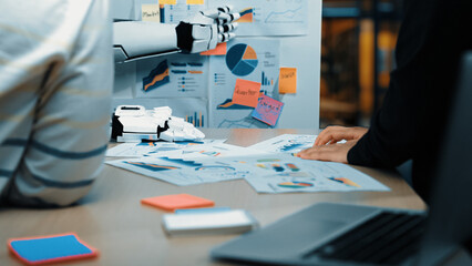 Poster - A business team engages with a futuristic robot assistant in a modern office setting, analyzing data charts and reports, enhancing collaboration and productivity.Noogenesis