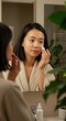 © salahudin - Woman applying face mask in bathroom